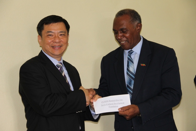 Republic of China (Taiwan) Ambassador to St. Kitts and Nevis His Excellency George Gow Wei Chiou (l) handing over a US$50,000 cheque, for the Nevis Cultural Development Foundation, to Premier of Nevis Hon. Vance Amory on April 19, 2016, at his Bath Hotel office